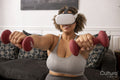 Woman in VR goggles exercising with dumbbells in living room