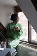 Smiling businesswoman holding cup of coffee while looking through window