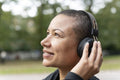 Close-up of smiling woman with headphones in park