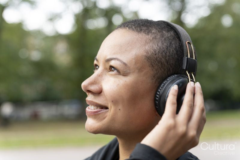 Close-up of smiling woman with headphones in park