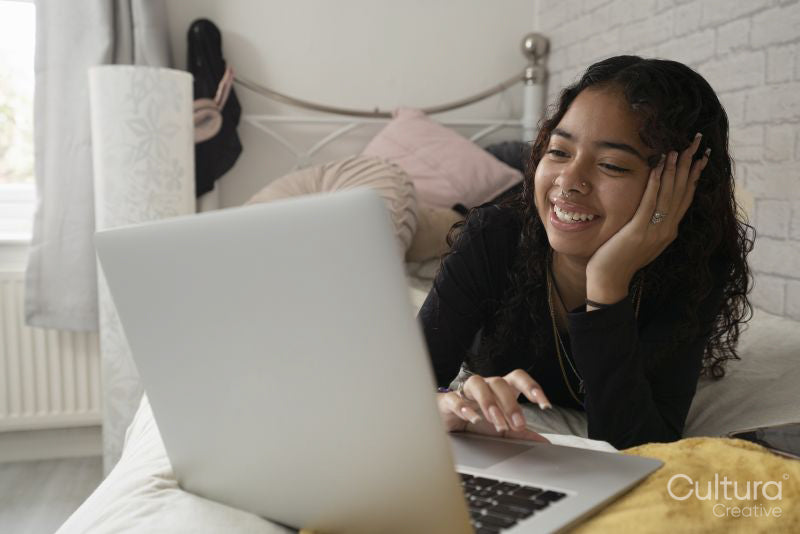 Teenage girl using laptop on bed at home