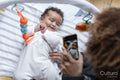 Mother photographing baby daughter with smart phone at home