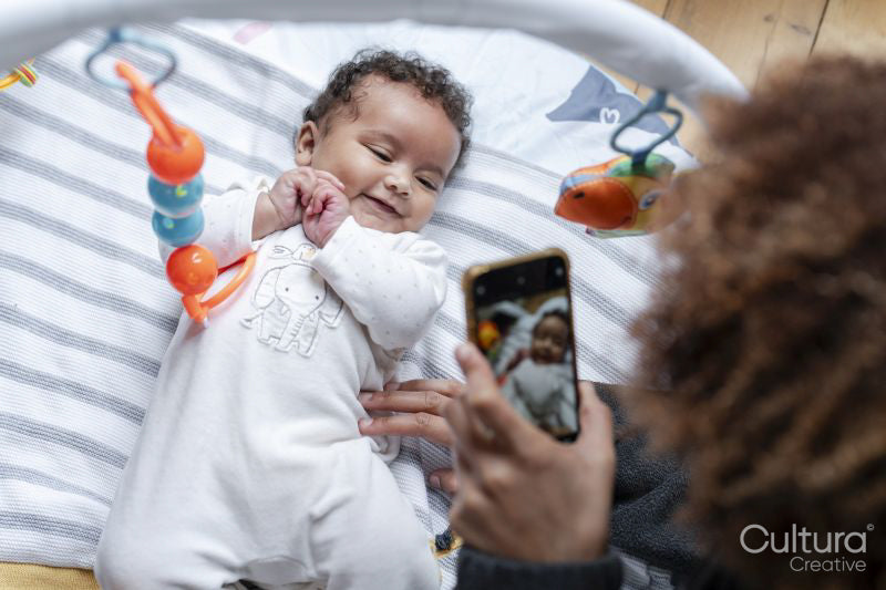 Mother photographing baby daughter with smart phone at home