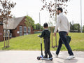Boy on push scooter walking with father to school