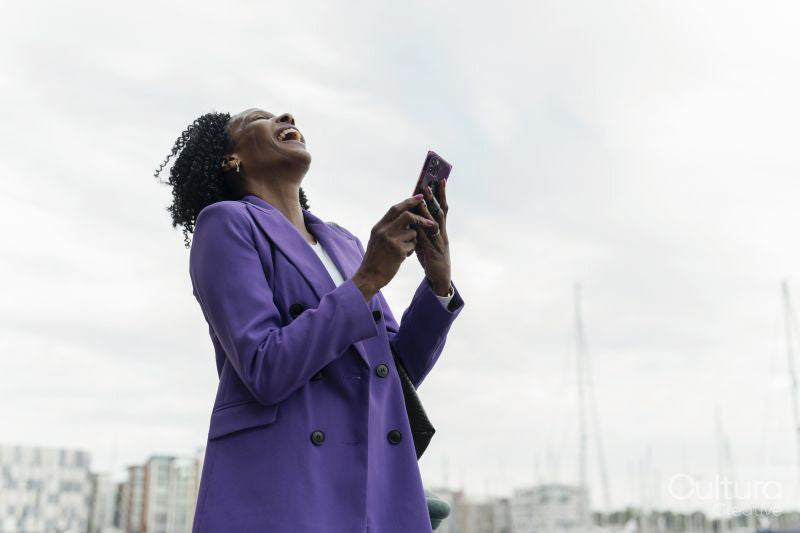 Woman laughing while using smart phone in city