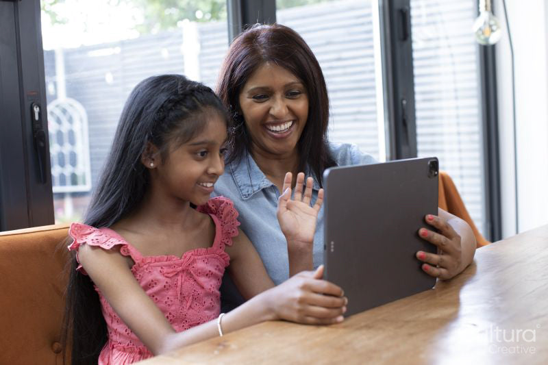 Smiling mother and daughter having video call at home