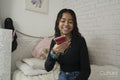 Teenage girl using smart phone on bed at home