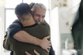 Male couple hugging at home