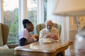 Smiling senior man and nurse playing cards at table in nursing home