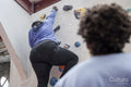 Daughter looking at mother climbing on bouldering wall