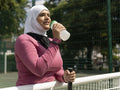 Sutton,Woman in headscarf drinking water from bottle on tennis court