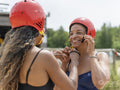 Woman helping friend putting on sports helmet