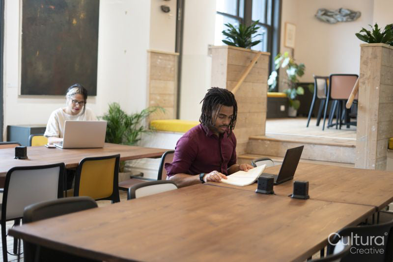 Man and woman working on laptops in office