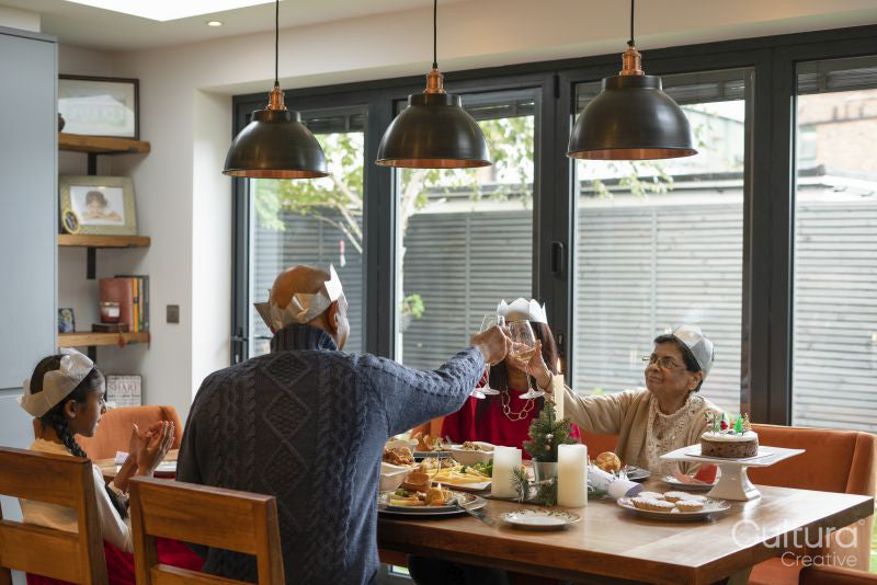 Family wearing paper crowns toasting during Christmas dinner