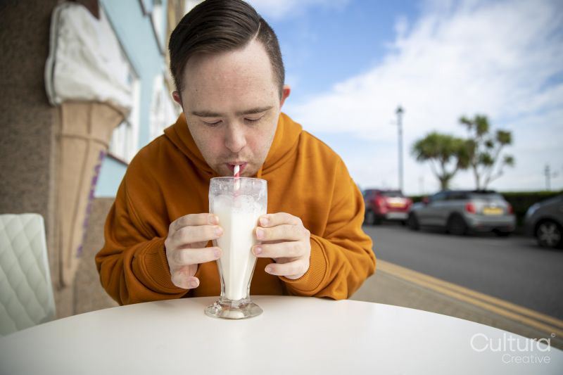 Man drinking milkshake in sidewalk cafe