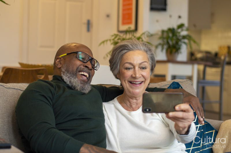Senior couple using smart phone at home