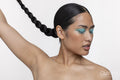 Portrait of woman with blue makeup, holding braid up