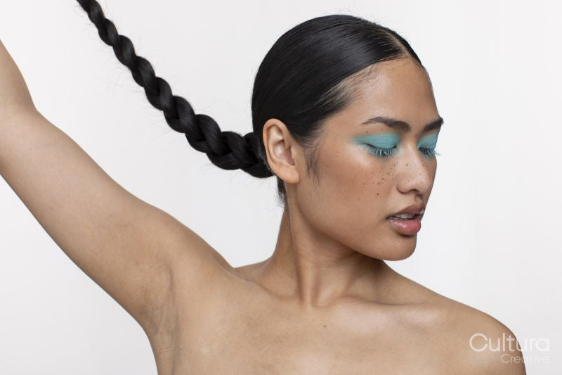 Portrait of woman with blue makeup, holding braid up