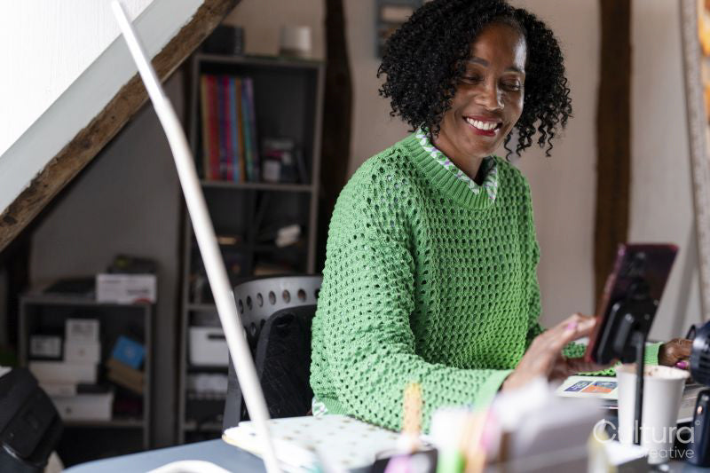 Smiling businesswoman using smart phone by desk in office