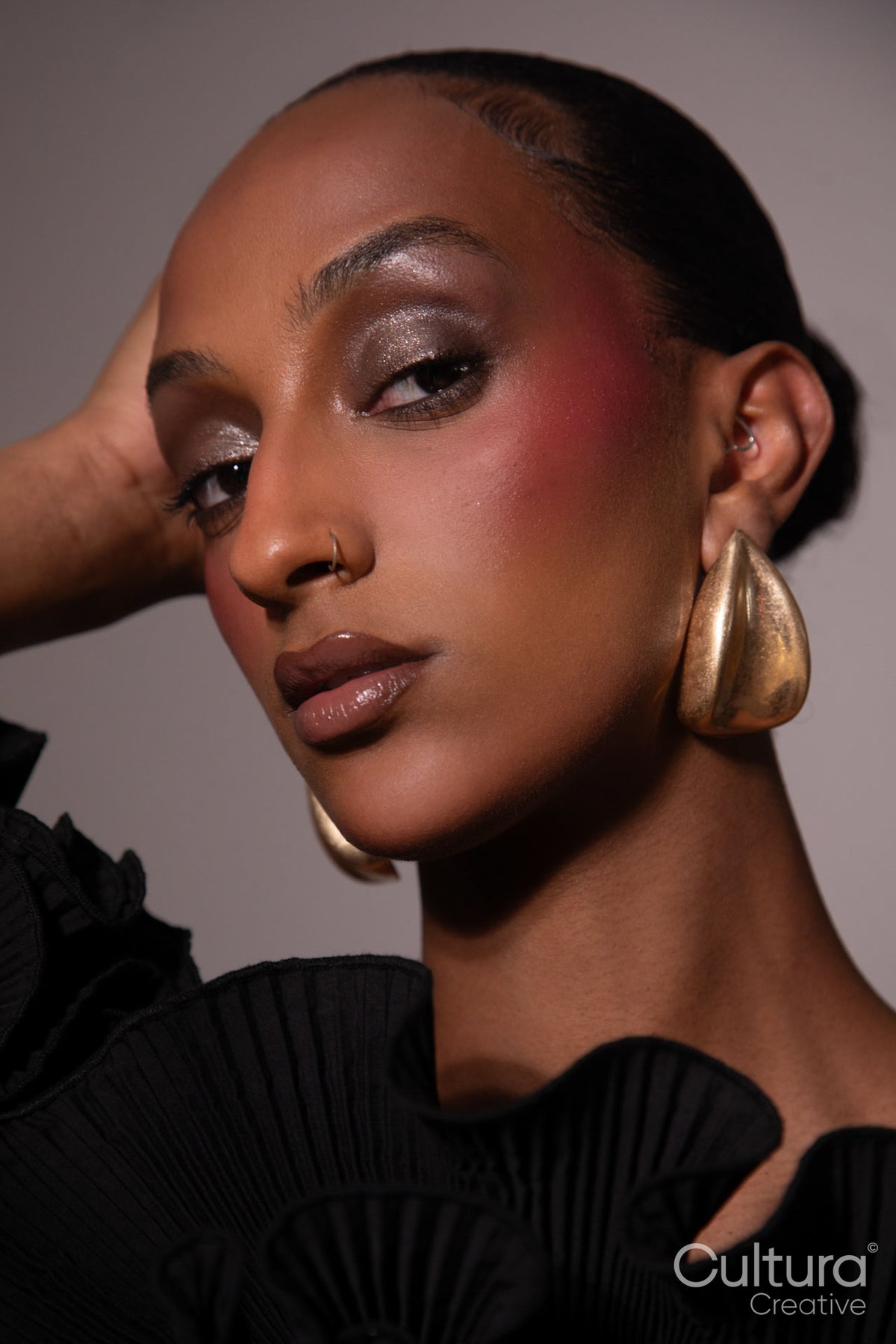 Woman in a black dress with gold earrings on a grey background