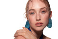 Studio portrait of a woman in a blue dress and large blue earrings