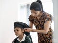 Mother wrapping traditional turban on sons head