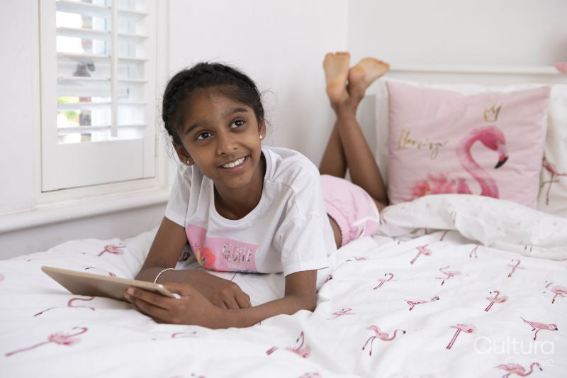 Smiling girl lying on bed with tablet