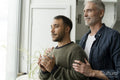 Mature male couple looking through window at home