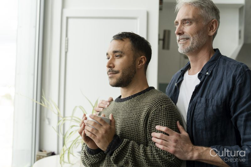Mature male couple looking through window at home