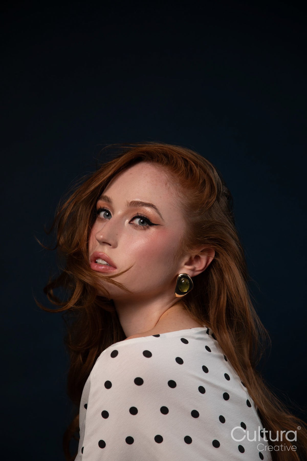 Studio portrait of a woman in a polka dot top with windswept hair