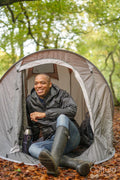 Smiling man sitting in tent in forest