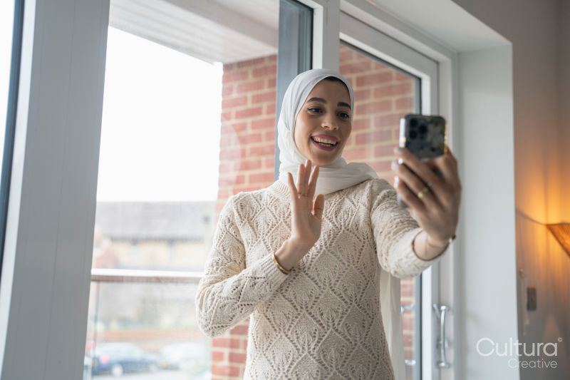 Smiling woman in hijab having video call on smart phone