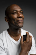 Portrait of man putting on perfume against gray background