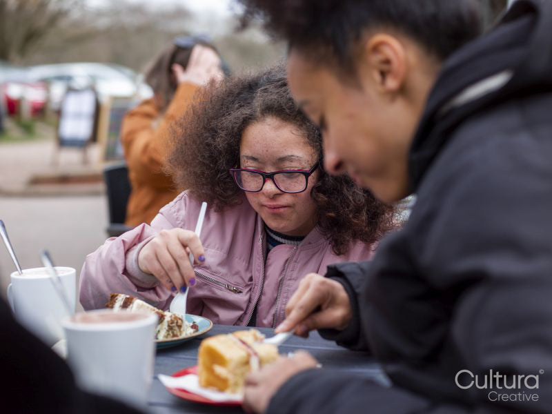 Two girls eating cakes in cafe