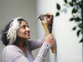 Woman hammering nail into house wall