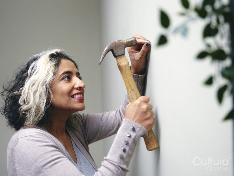 Woman hammering nail into house wall