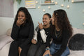 Laughing teenage friends sitting on bed in bedroom