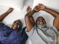 Overhead view of happy mature couple lying on bed in hotel room