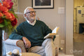 Smiling senior man sitting in armchair and reading book