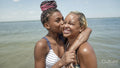 Girl kissing smiling mother on beach