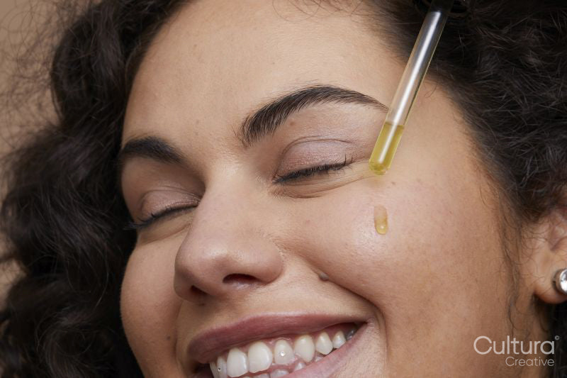 Close-up of young woman applying face serum