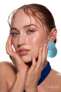 Studio portrait of a woman in a blue dress and large blue earrings