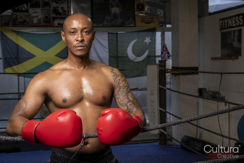 Mature man wearing boxing gloves in boxing ring, portrait