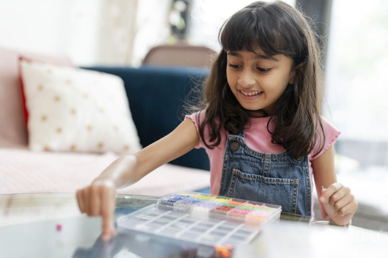 Little girl playing with beads in living room