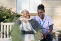 Smiling nurse and senior woman in wheelchair relaxing in park