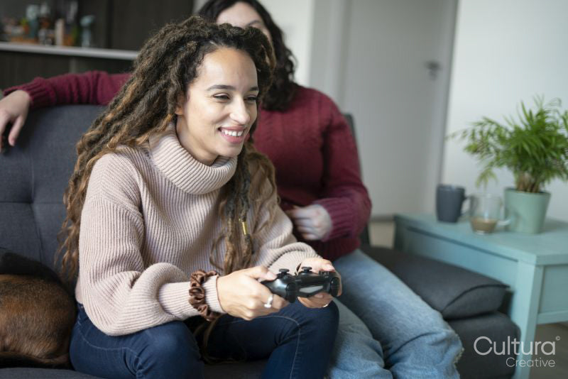 Two women sitting on sofa and playing video game