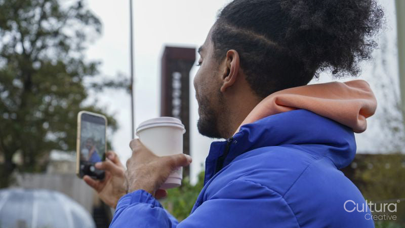 Young man holding phone and coffee