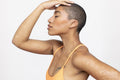 Profile of woman wearing orange top touching head