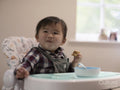 Baby boy sitting in high chair and eating