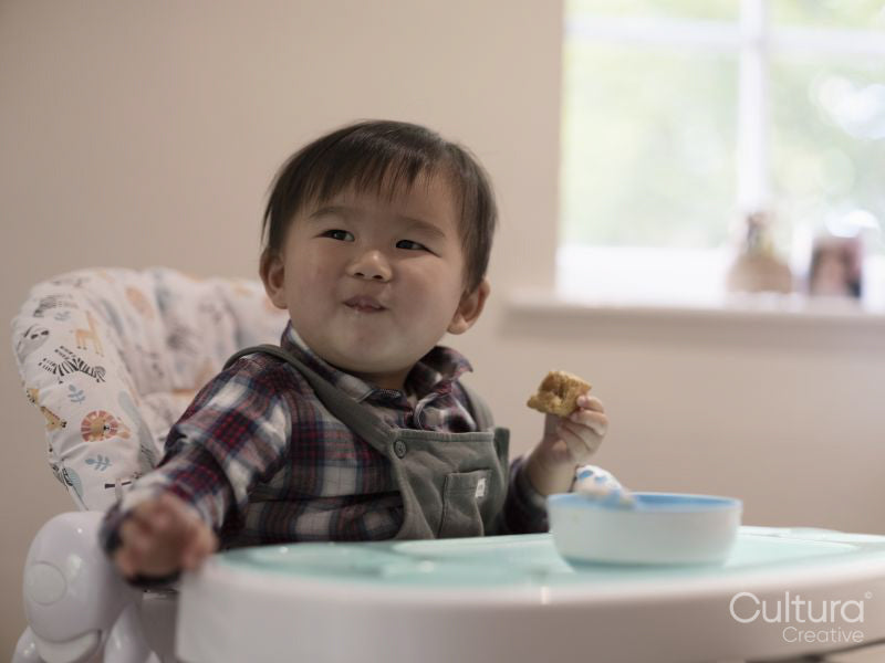 Baby boy sitting in high chair and eating